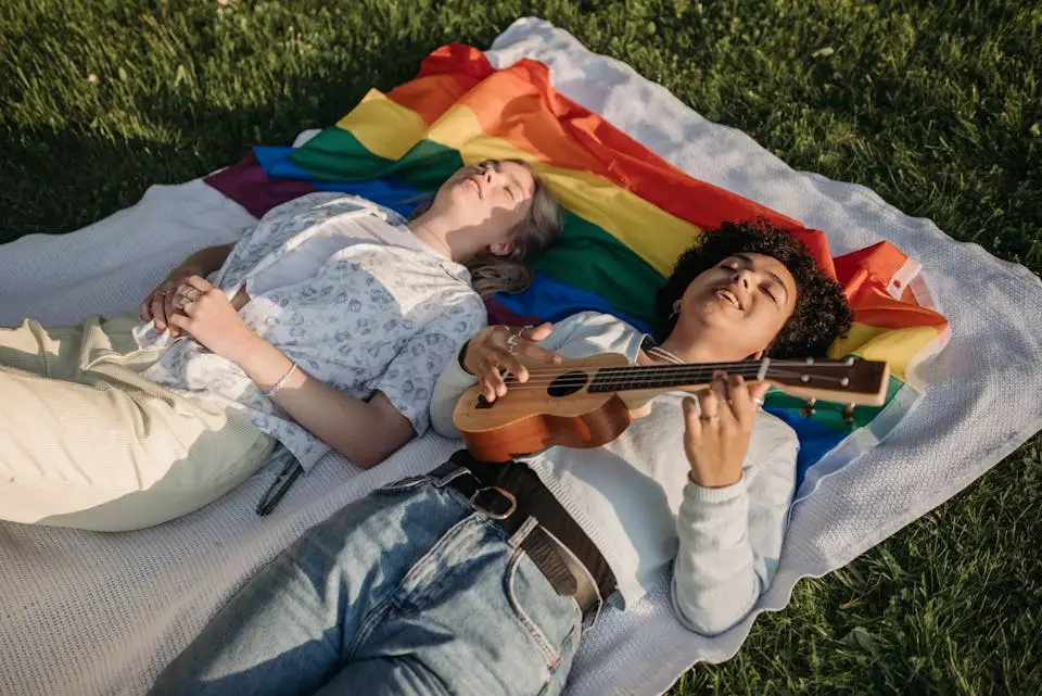 girls smiling laying down on rainbow flag and green grass